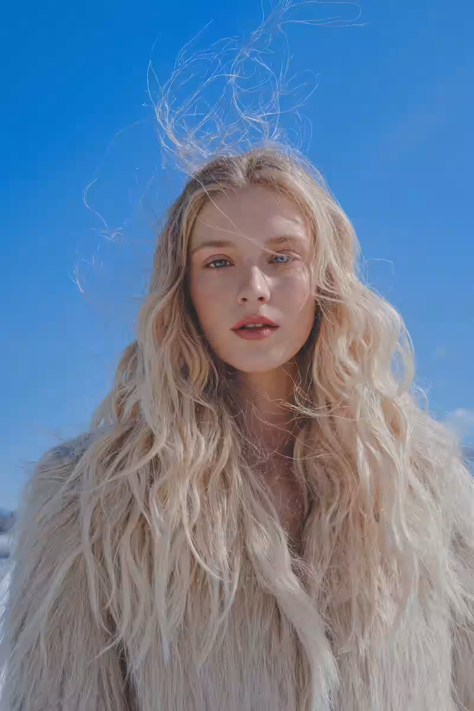 Portrait of a woman with long pale blonde hair against a bright blue sky
